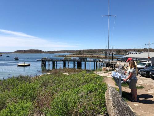 a woman sitting on a bench next to a body of water at Rhumb Line Resort in Kennebunkport