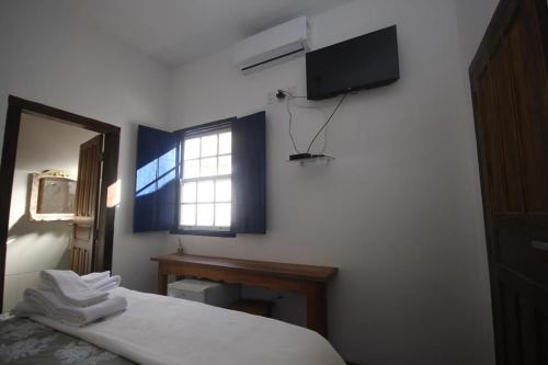 a bedroom with a bed and a window and a television at Pousada Sinhá Vilaça in Tiradentes