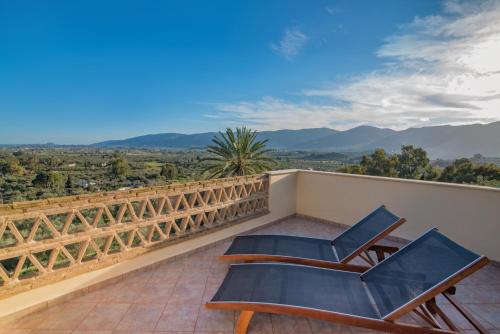 twee stoelen op een balkon met bergen op de achtergrond bij Villas Lugrezia Sea View in Méson Yerakaríon