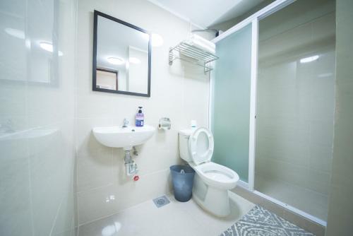 a bathroom with a toilet and a sink and a shower at The Partridge Guesthouse in Cebu City