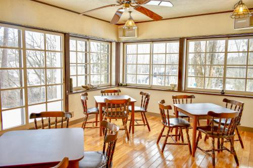 a dining room with tables and chairs and windows at Panketo Lodge & Yoga Studio in Hakuba