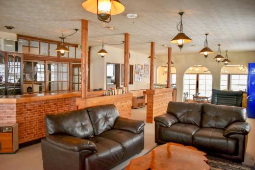 a living room with two leather couches and a bar at Panketo Lodge & Yoga Studio in Hakuba