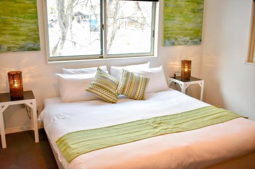 1 dormitorio con 1 cama con 2 mesitas de noche y 2 ventanas en Altitude Apartments Hakuba, en Hakuba