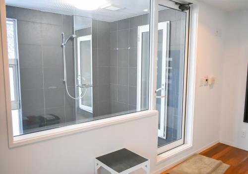 Un baño con ducha con ventana de cristal. en Altitude Apartments Hakuba, en Hakuba