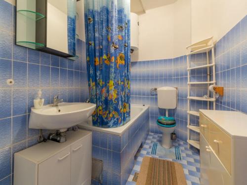 a blue tiled bathroom with a sink and a toilet at Apartments LUMAR in Dramalj
