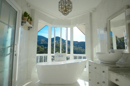 a white bathroom with two sinks and a large window at Luxe Wilderness in Nuwara Eliya