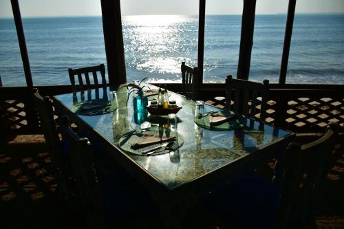 a glass table with chairs and the ocean in the background at Mediterraneo Boutique Hotel in Dar es Salaam