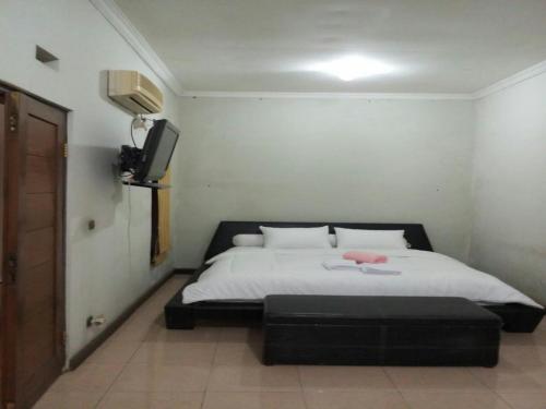 1 dormitorio con 1 cama y TV en la pared en Seventeen homestay, en Bandung