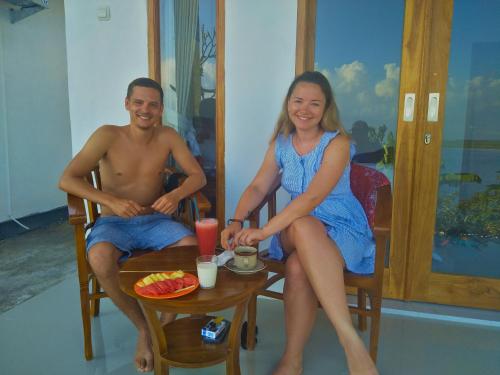 un uomo e una donna seduti a un tavolo di Prasi Sunset Bungalows a Nusa Penida