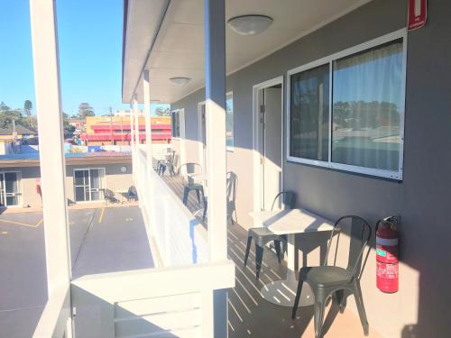 a balcony with chairs and a table and a window at Toukley Motor Inn in Toukley