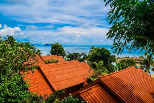 a group of roofs with the ocean in the background at Zama Resort Koh Phangan in Haad Chao Phao