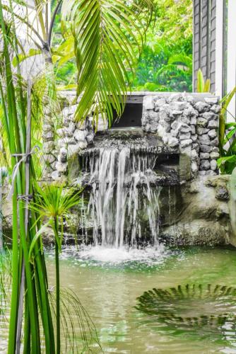 a waterfall in a pond in a garden at Zama Resort Koh Phangan in Haad Chao Phao