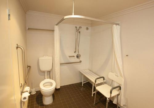 a bathroom with a toilet and a bench in it at Wine Country Motor Inn in Cessnock
