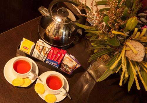 a table with two cups of tea and a tea kettle at Wine Country Motor Inn in Cessnock