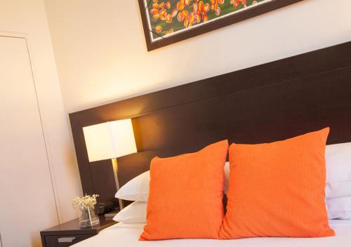 a bed with orange pillows and a black headboard at Wine Country Motor Inn in Cessnock