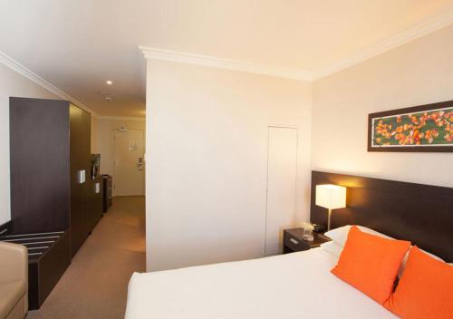 a bedroom with a white bed with orange pillows at Wine Country Motor Inn in Cessnock