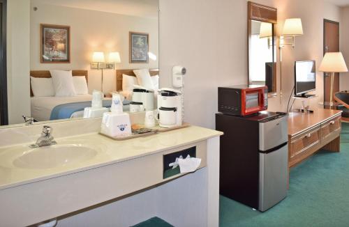 a hotel room with a bathroom with a bed and a sink at Americas Best Value Inn & Suites - Tahquamenon Country in Newberry