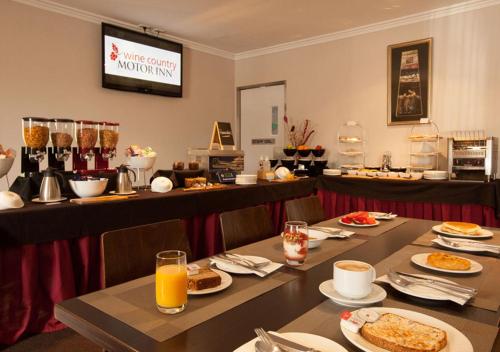 a breakfast room with tables with food and orange juice at Wine Country Motor Inn in Cessnock