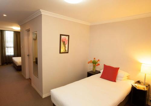 a bedroom with a white bed with a red pillow at Wine Country Motor Inn in Cessnock