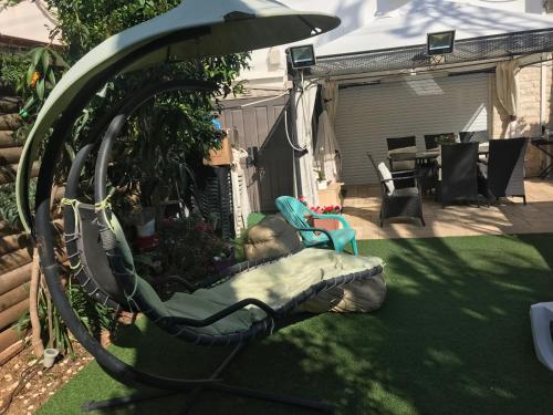 a garden with a chair and a swing at Charming Unit with Pool and Great Amenities in Rishon LeẔiyyon