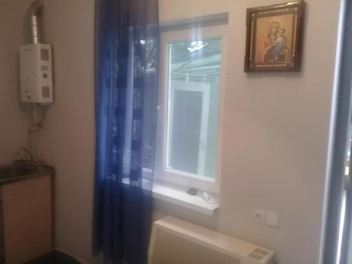 a bathroom with a window and a blue shower curtain at Guest House Gikacha in Tbilisi City