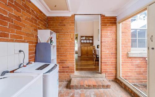 a kitchen with a brick wall and a white refrigerator at Eliza 1875 Red Brick Duplex Townhouse in Grafton