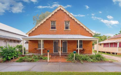 a red brick house with a porch on a street at Eliza 1875 Red Brick Duplex Townhouse in Grafton