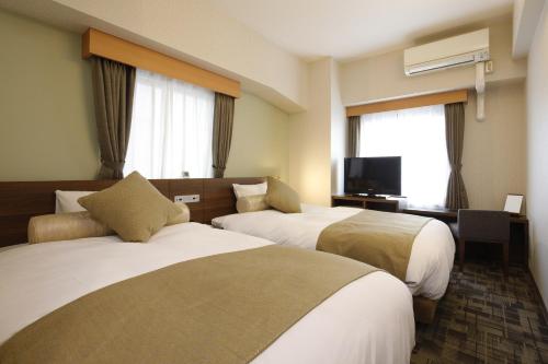 横浜市にあるレンブラントスタイル横浜関内のベッド2台、薄型テレビが備わるホテルルームです。