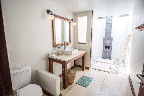 a bathroom with a sink and a toilet and a mirror at Island View Bar & Bungalow in Gili Air