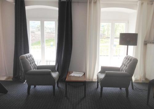a living room with two chairs and a table and windows at Mosel - River - Quartier 31 in Lieser