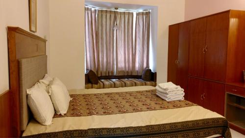 a bedroom with a bed with a chair and a window at Sai Towers in Puttaparthi