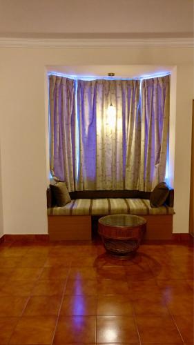 a living room with a couch in front of a window at Sai Towers in Puttaparthi