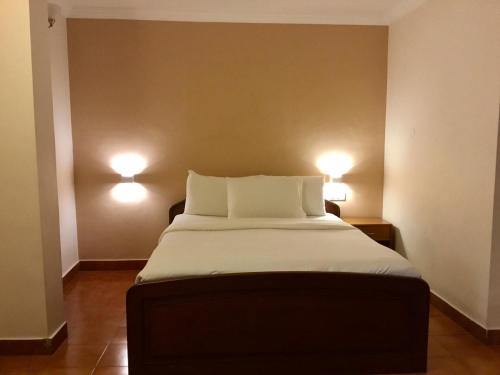 a bed in a room with two lights on the wall at Sai Towers in Puttaparthi