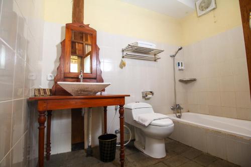 een badkamer met een wastafel, een toilet en een bad bij Cempaka Villa in Borobudur