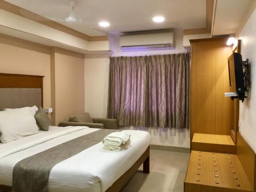 a hotel room with a bed and a chair at Sai Towers in Puttaparthi