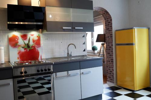 - une cuisine avec un évier et une cuisinière avec une tomate sur le mur dans l'établissement Taunushome, à Bad Camberg