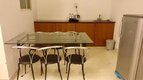 a kitchen with a glass table and four chairs at Sai Towers in Puttaparthi