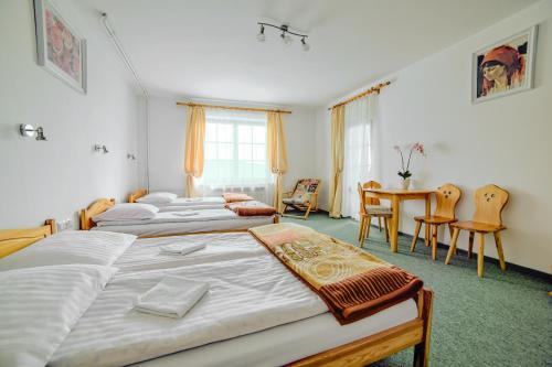 drie bedden in een kamer met een tafel en stoelen bij Villa Medica in Rabka