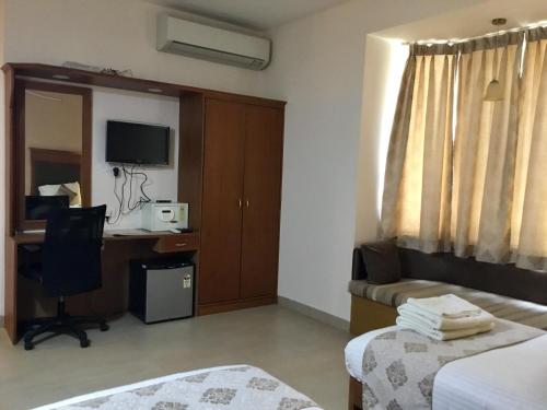 a hotel room with a desk and a computer in it at Sai Towers in Puttaparthi