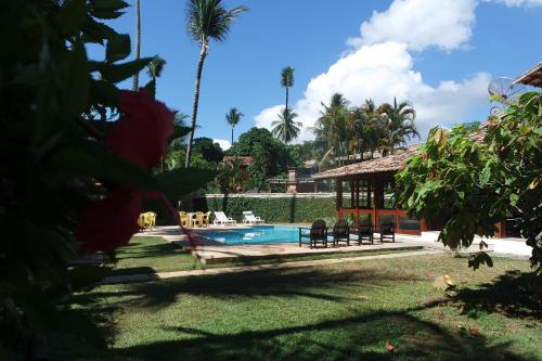 a pool with a gazebo and palm trees at Residencial Frente a Praia in Porto Seguro