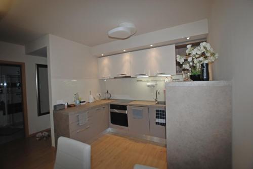 a kitchen with white cabinets and a vase of flowers at Silver DeLux Apartman in Balatonfüred