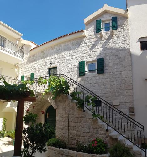 a stone building with stairs and green shutters at Apartments Dvor - ap1, ap2, ap3 in Baška Voda