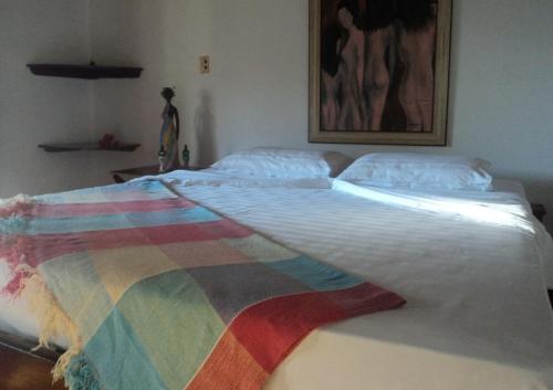 a large bed with a colorful blanket on it at Pousada Bangalô in Jericoacoara
