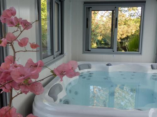 La salle de bains est pourvue d'une baignoire avec des fleurs roses. dans l'établissement La Roulotte du Domaine de Meigné, à Meigné