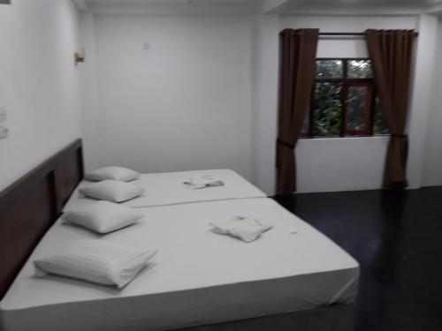 two beds in a room with a window at The Kingston Hotel in Kiribathgoda