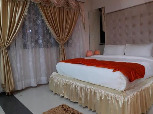 una camera da letto con un grande letto con una coperta rossa di Setrac Orange a Navi Mumbai