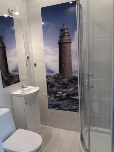 a bathroom with a shower and a lighthouse painting on the wall at Orzechowa Przystań in Ustka