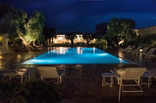 a swimming pool at night with chairs around it at Masseria Torre Del Diamante in Torre Canne