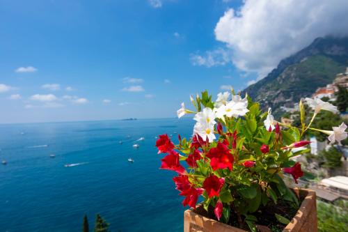 a bouquet of flowers in a pot overlooking the ocean at Villa Pietra Santa in Positano