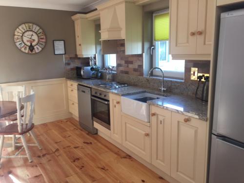 a kitchen with white cabinets and a stove top oven at A Selection of Self Catering Holiday Homes at Kilcloon Cottages in Maynooth
